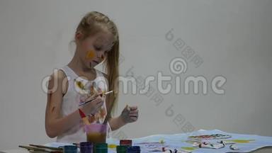 可爱的小女孩画家在桌子上<strong>画画</strong>，在她的衣服上<strong>画画</strong>。 慢动作